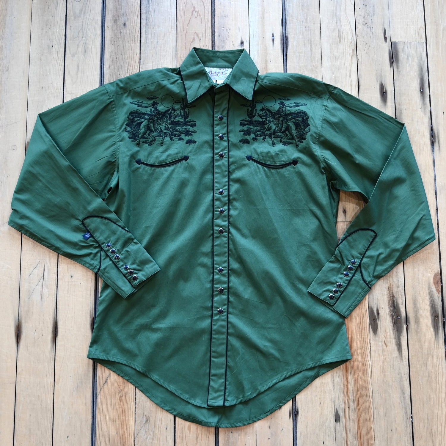 View of Green Western shirt with embroidered “man and rider” motif across yokes and cuffs