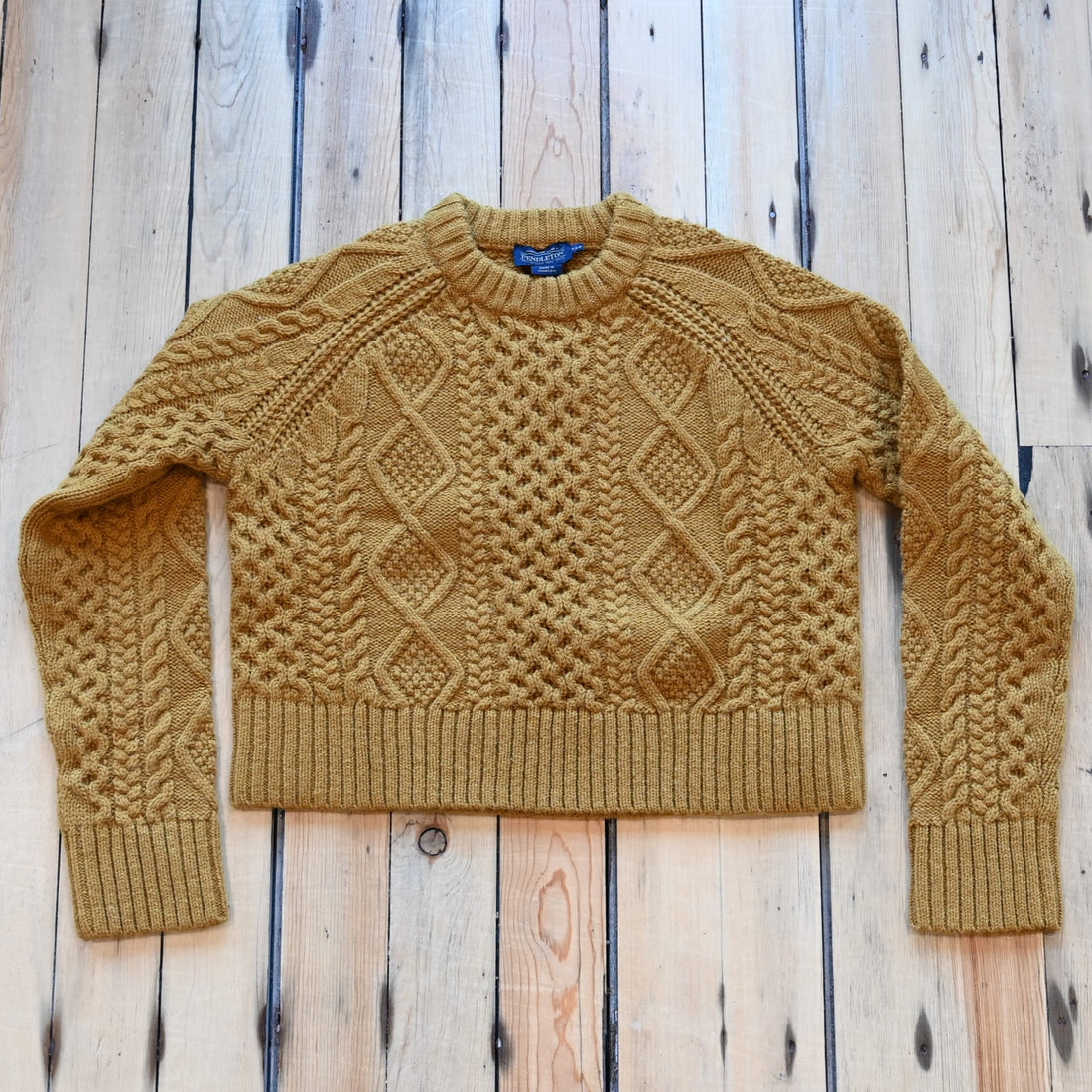 View of Pendleton cropped lambswool sweater in Deep Gold with cable knit pattern
