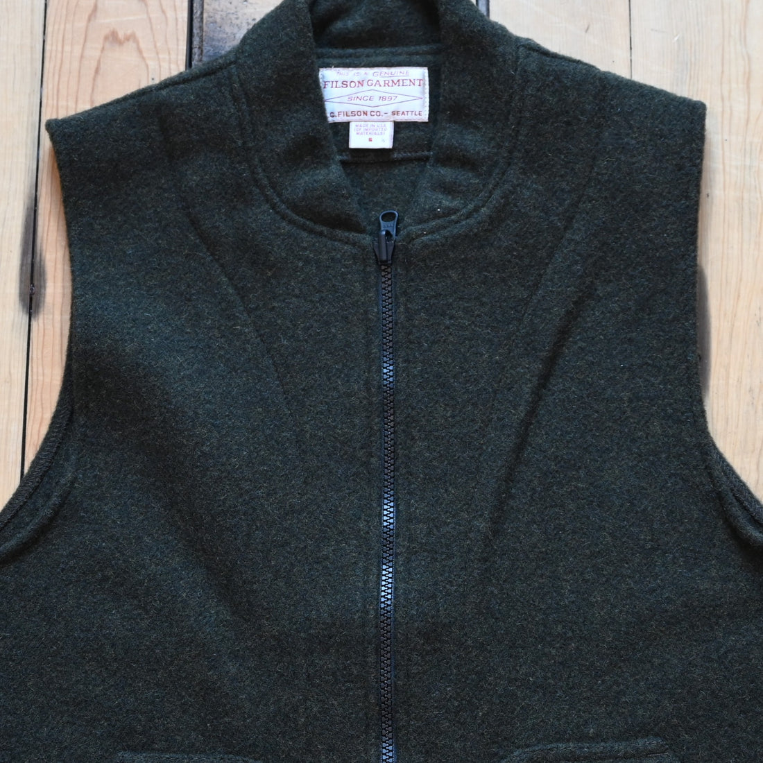 Forest green Filson Mackinaw Wool Vest Liner with zip-front, hand-warmer pockets, standing collar, and drawcord waist