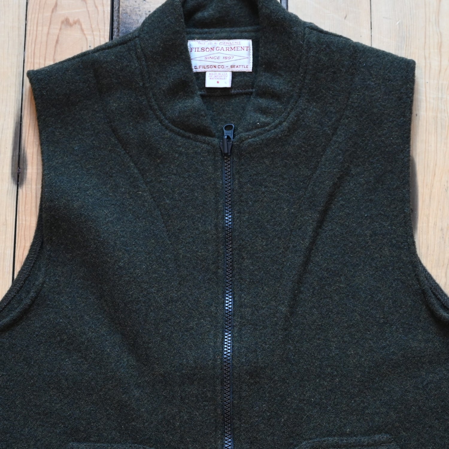 Forest green Filson Mackinaw Wool Vest Liner with zip-front, hand-warmer pockets, standing collar, and drawcord waist