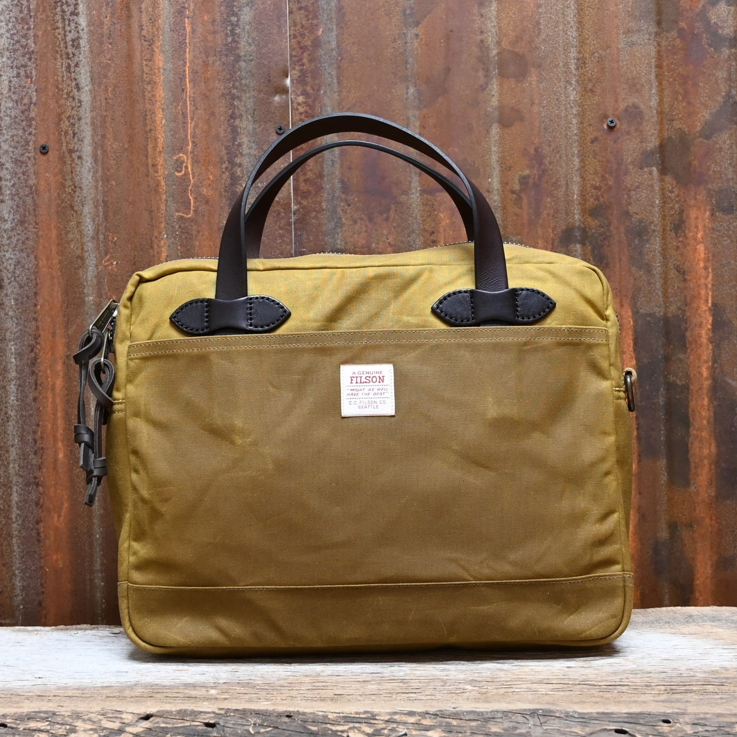 View of Filson Tin Cloth Compact Briefcase in Dark Tan, showcasing its durable waxed cotton exterior, leather handles, and padded laptop compartment