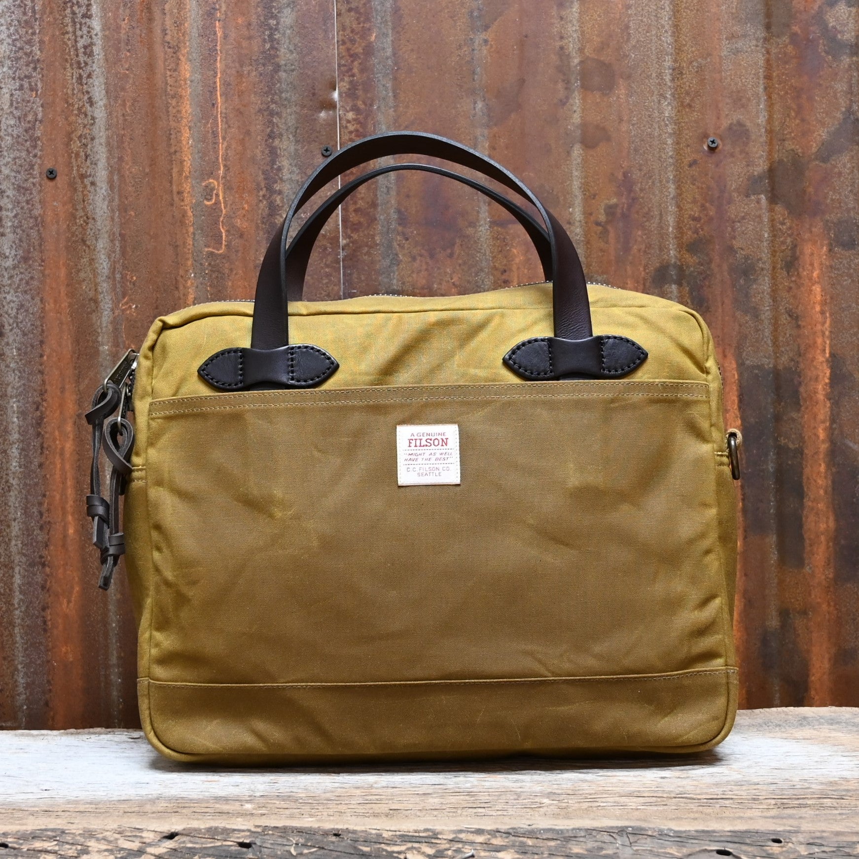 View of Filson Tin Cloth Compact Briefcase in Dark Tan, showcasing its durable waxed cotton exterior, leather handles, and padded laptop compartment