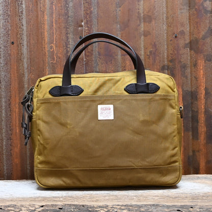 View of Filson Tin Cloth Compact Briefcase in Dark Tan, showcasing its durable waxed cotton exterior, leather handles, and padded laptop compartment