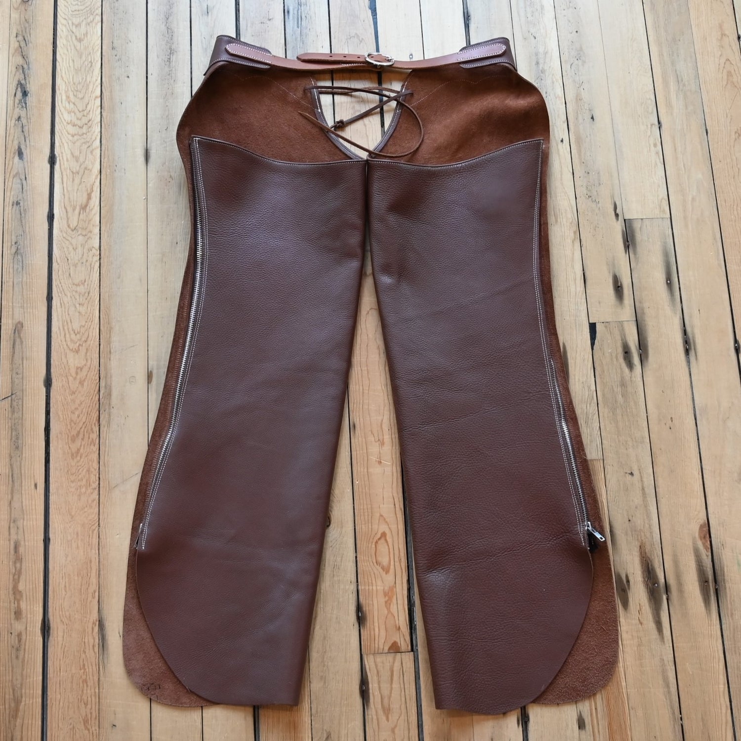 View of Weaver Shotgun Full Grain Chaps in brown oil-tanned leather with adjustable closures.