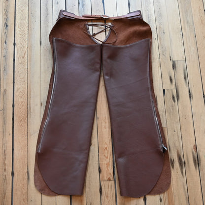 View of Weaver Shotgun Full Grain Chaps in brown oil-tanned leather with adjustable closures.