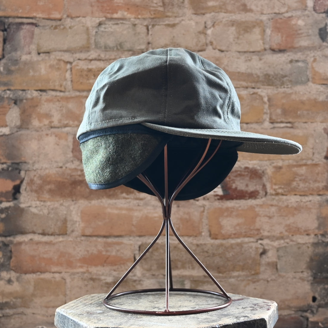 View of Filson Insulated Tin Cloth Cap in Otter Green featuring wool ear/neck flap and 3&quot; pre-curved bill