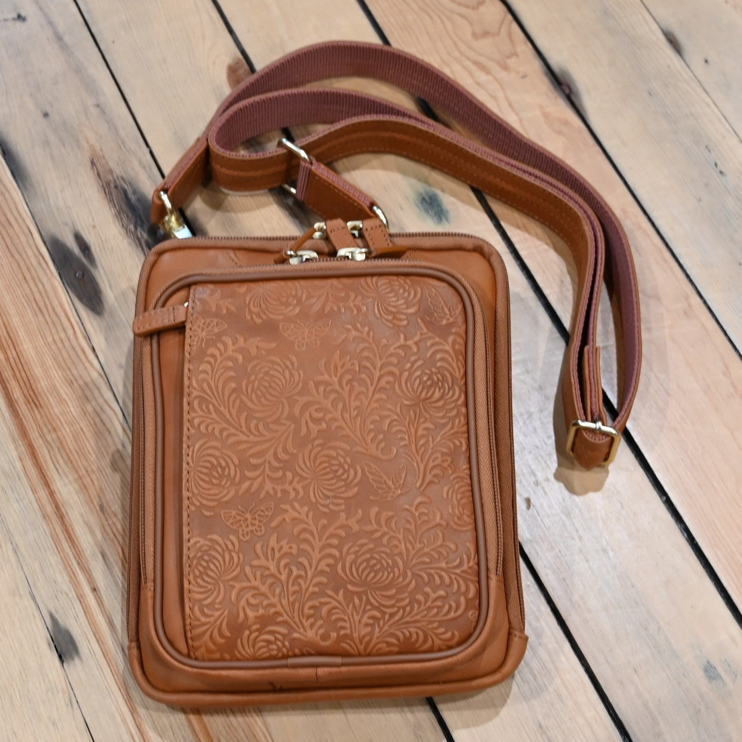 Tan leather crossbody shoulder pouch with embossed front, designed for concealed carry