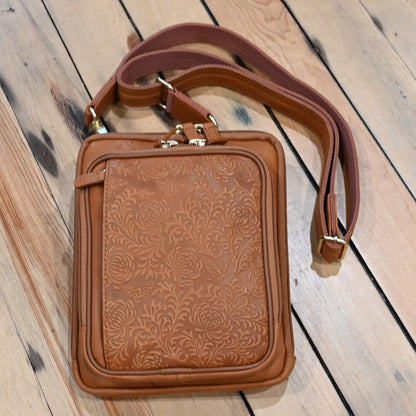 Tan leather crossbody shoulder pouch with embossed front, designed for concealed carry