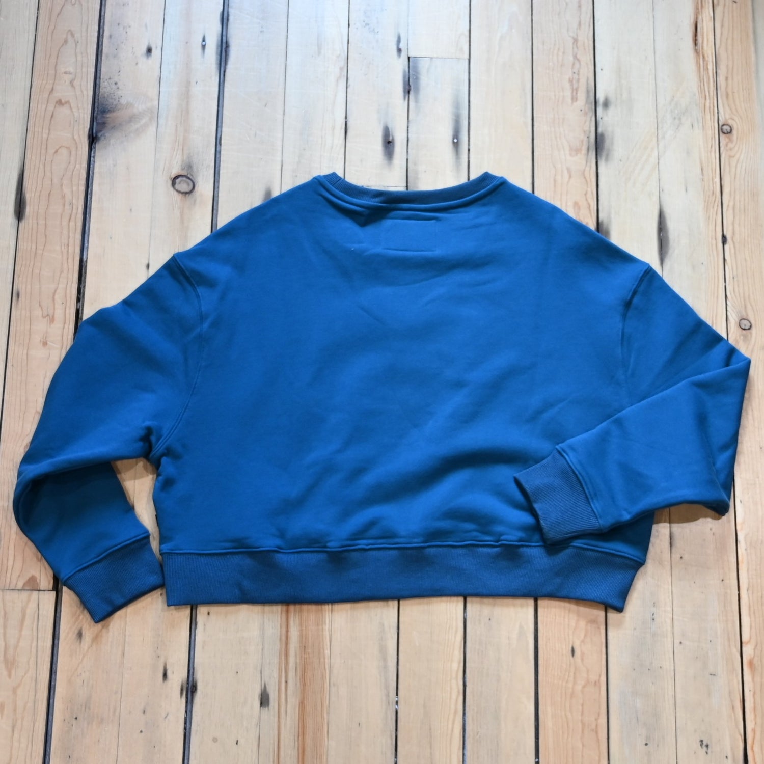 View of Kimes Ranch Ladies Colfax Crew Sweatshirt in Mid Blue, featuring an oversized fit, ribbed hem, and embroidered logo