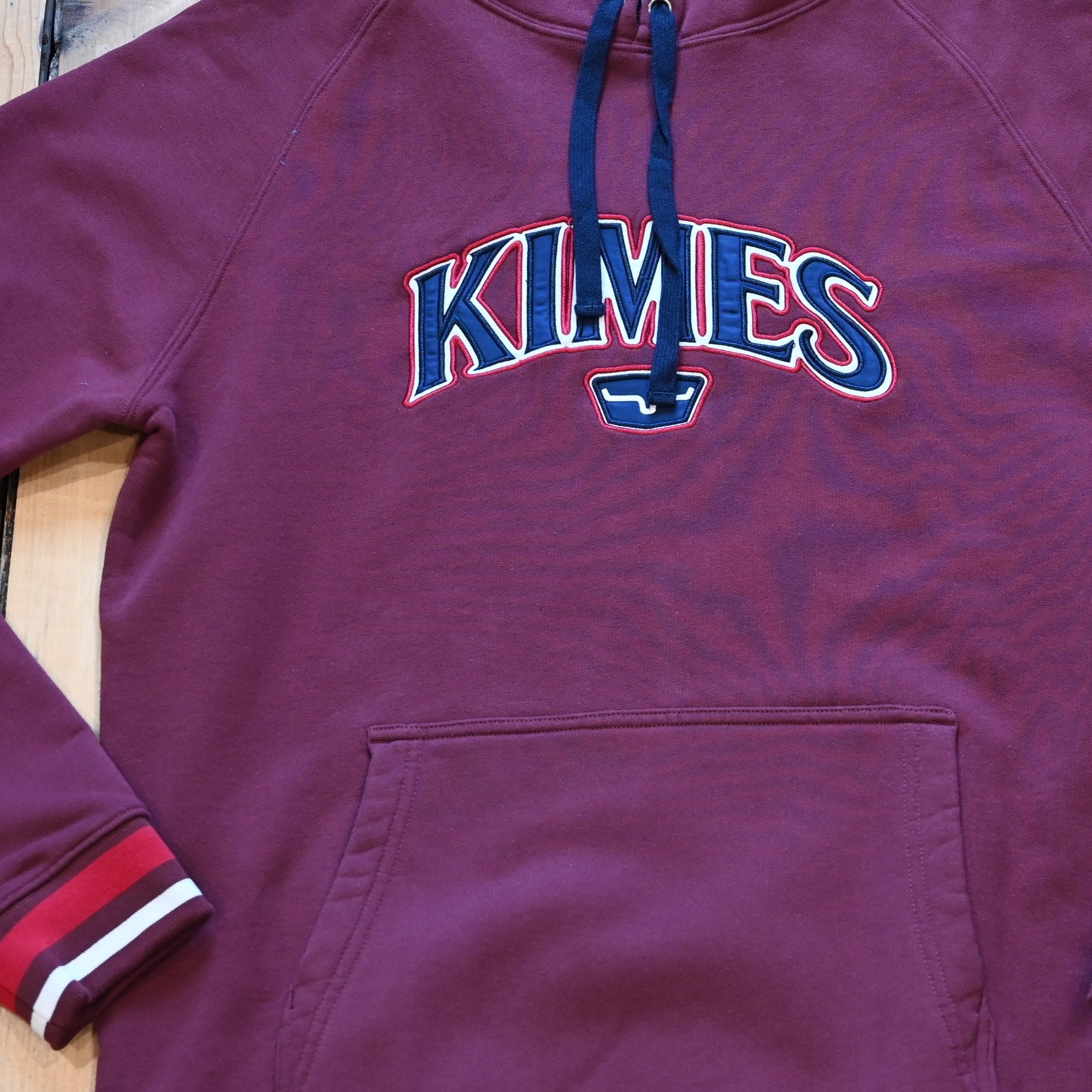 View of Kimes Ranch Kubo Sweatshirt in Burgundy, featuring a vibrant striped bottom and embroidered logo