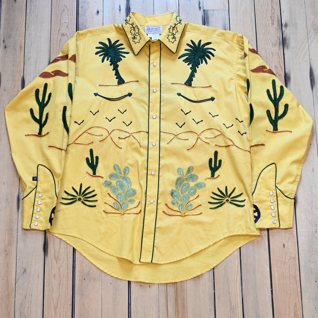 View of Rockmount men’s gold western shirt with wagon embroidery and sawtooth pockets