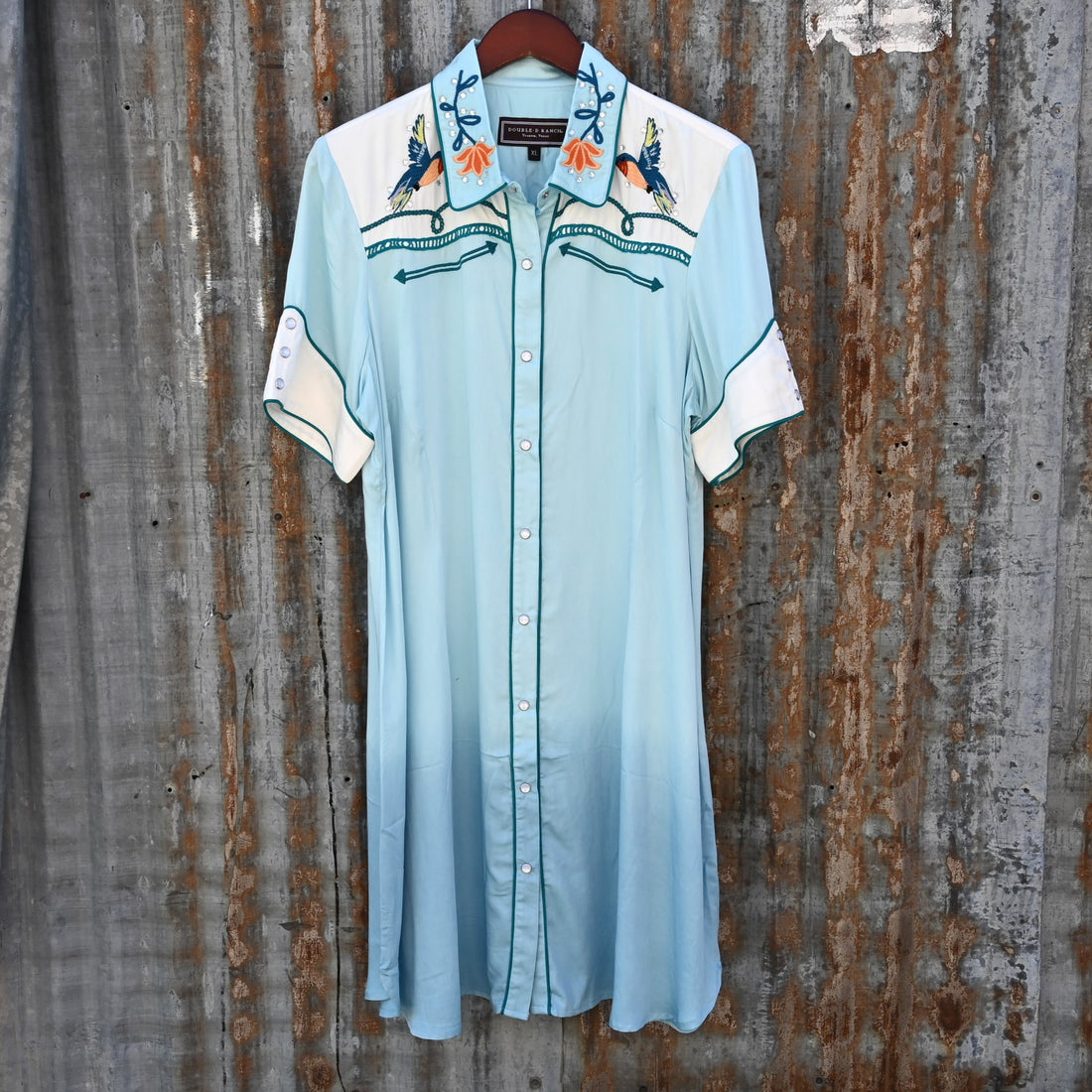 View of Double D Ranch Senoritas Rodeo Dress in Celestial Sky featuring embroidered floral print, pearl snap button closure, and drawstring waist