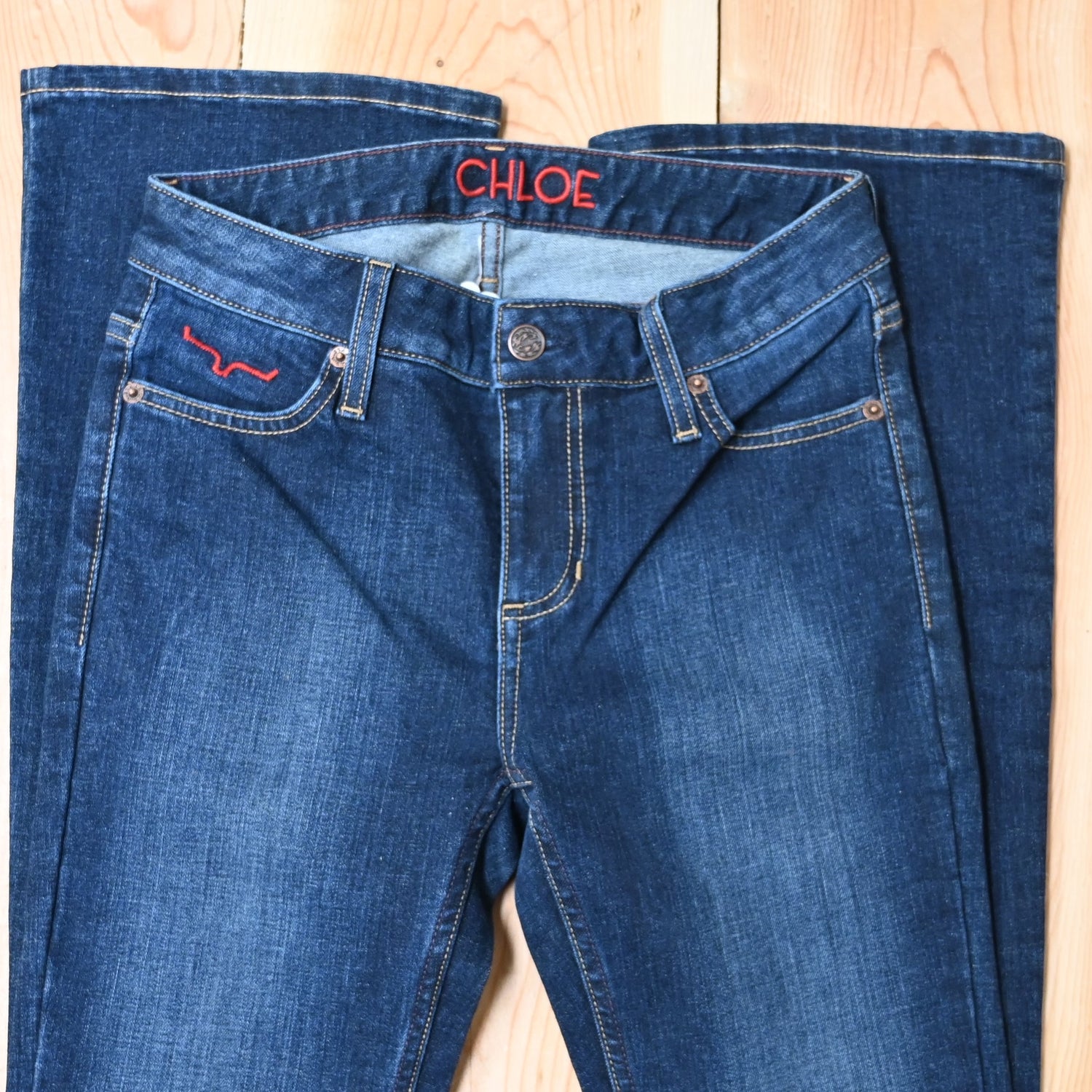 View of Kimes Ranch Chloe Jeans in Blue, featuring a mid-rise waist, fitted thigh, and flare bootcut leg with hand-sanded details