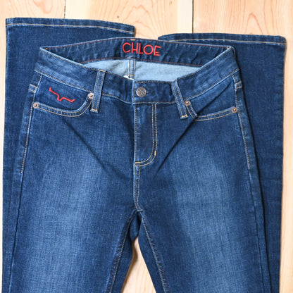 View of Kimes Ranch Chloe Jeans in Blue, featuring a mid-rise waist, fitted thigh, and flare bootcut leg with hand-sanded details